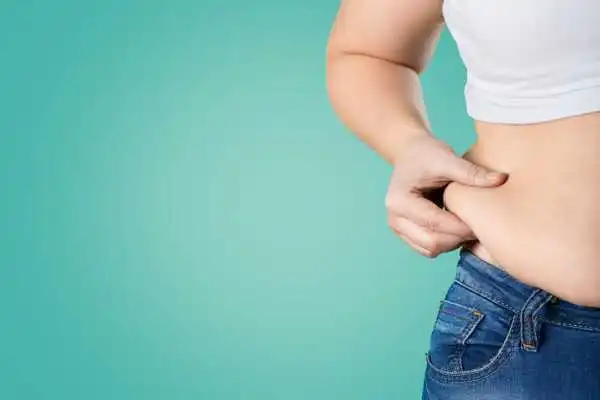 Image of woman pinching her love handles to show weight gain Sunbury
